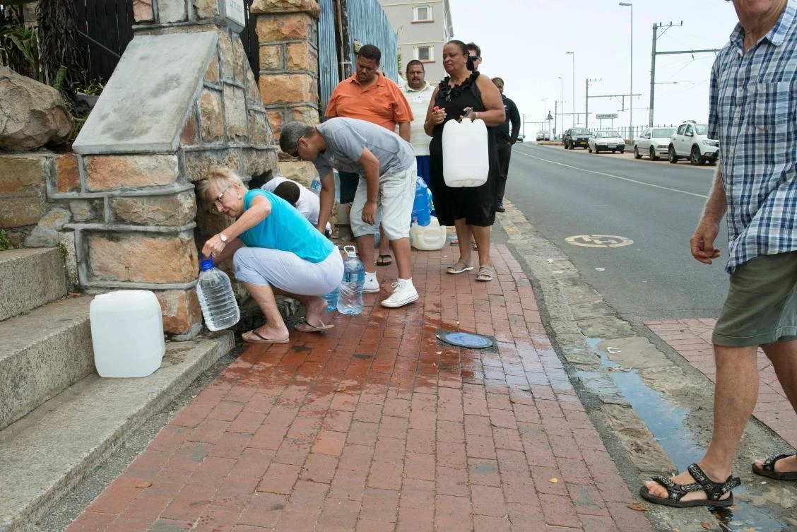 People collect drinking water from pipes fed by an underground spring in St. James, Cape Town. The city is in the grip of a three-year-long drought. (AFP)