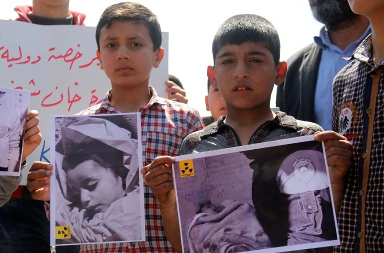 Syrian residents of Khan Sheikhun hold placards and pictures during a protest condemning a suspected chemical weapons attack on their town that killed at least 86 people. (AFP)