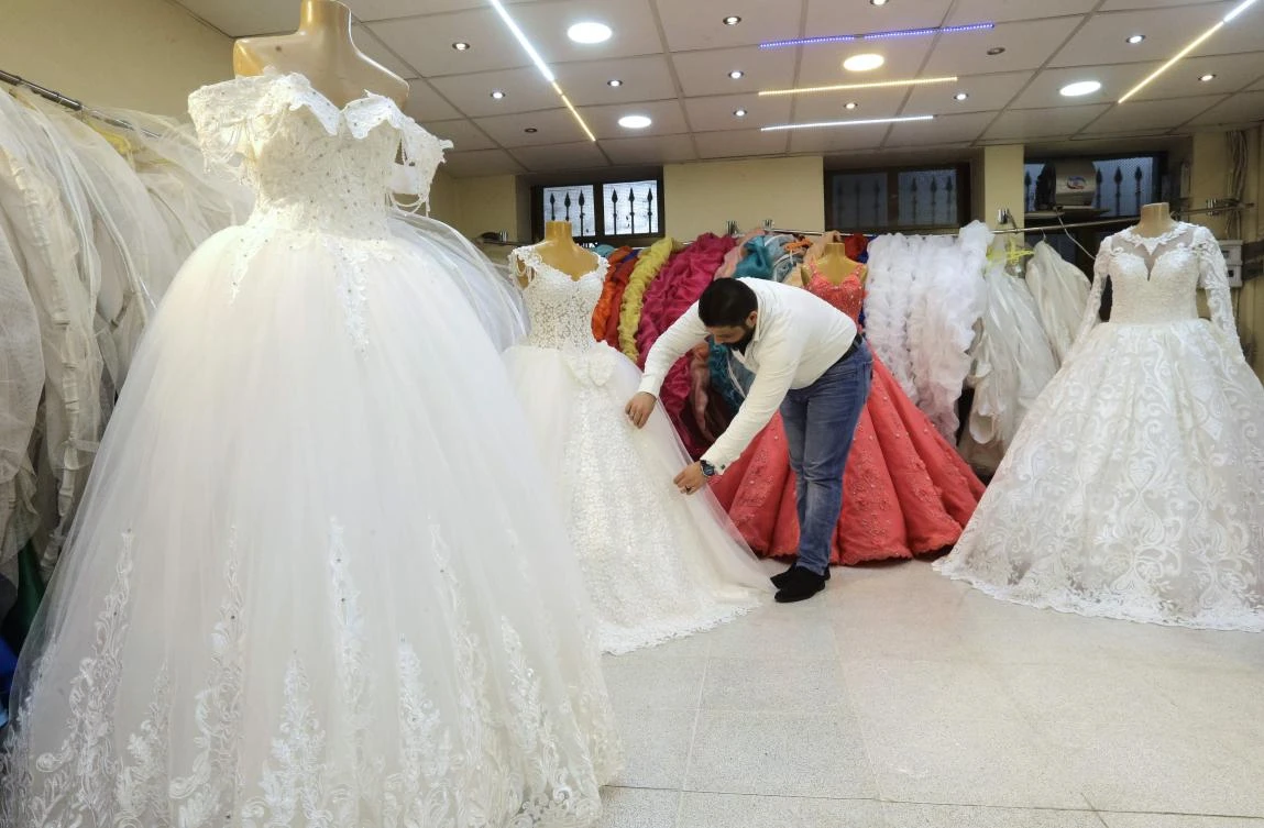 A picture taken on January 8, 2018 shows a Syrian man arranging dresses at a wedding dresses shop in the capital Damascus. (AFP)