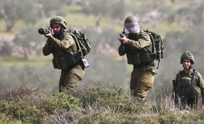 Israeli soldiers aim their weapons towards Palestinian protestors just outside of Nablus. (AFP)