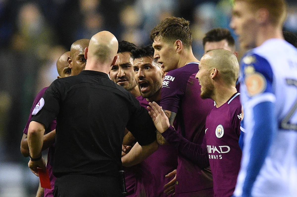 Referee Anthony Taylor (L) talks to Manchester City players after giving a red card to Manchester City's English midfielder Fabian Delph during the English FA Cup fifth round football match between Wigan Athletic and Manchester City at the DW Stadium in Wigan, northwest England, on Feb. 19, 2018. (Oli Scarff/AFP)