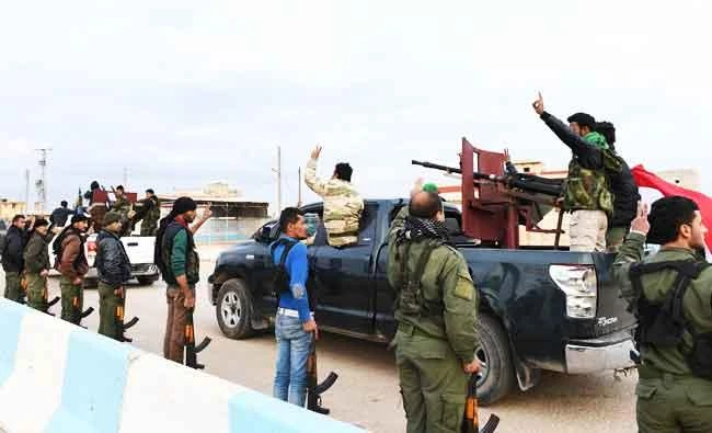 A photo taken on February 20, 2018 shows a convoy of pro-Syrian government fighters flashing the victory gesture as they ride through the windows of pickup trucks upon arriving in Syria's northern region of Afrin. (AFP)