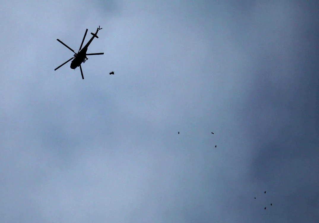 A picture taken on February 20, 2018 shows a Russian-made Syrian army attack helicopter dropping a payload over the rebel-held town of Arbin, in the besieged Eastern Ghouta region on the outskirts of the capital Damascus. (Amer Al-Mohibany/AFP)