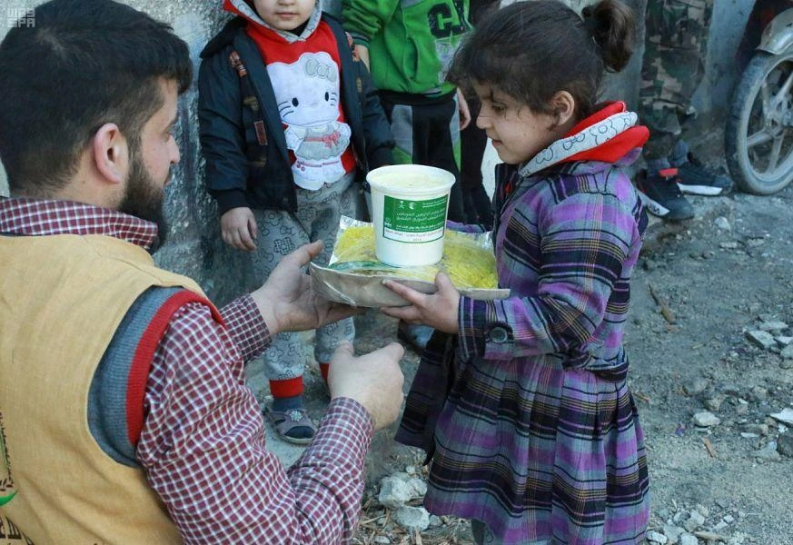 A young girl receives food aid. (Al-Ekhbariya)