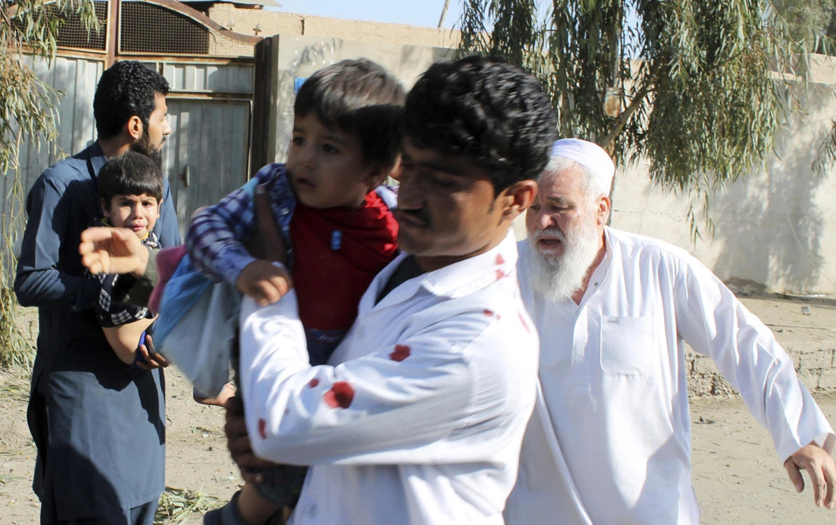 Men carry children away from an explosion site in Lashkar Gah, capital of southern Helmand province, Afghanistan, Saturday, Feb. 24, 2018. (AP)