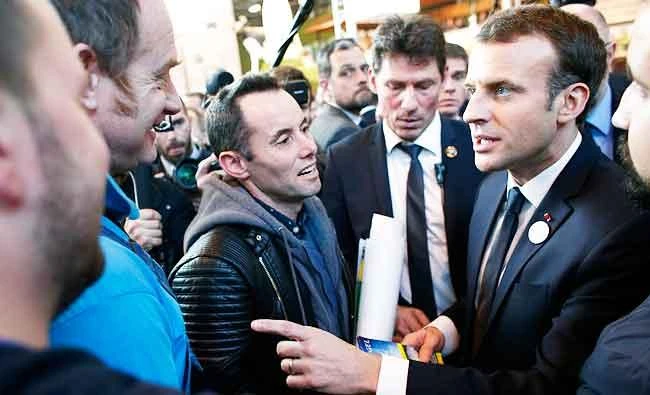 French President Emmanuel Macron, right, talks with farmers as he visits the 55th International Agriculture Fair at the Porte de Versailles exhibition center in Paris, France, on Saturday. (AP)