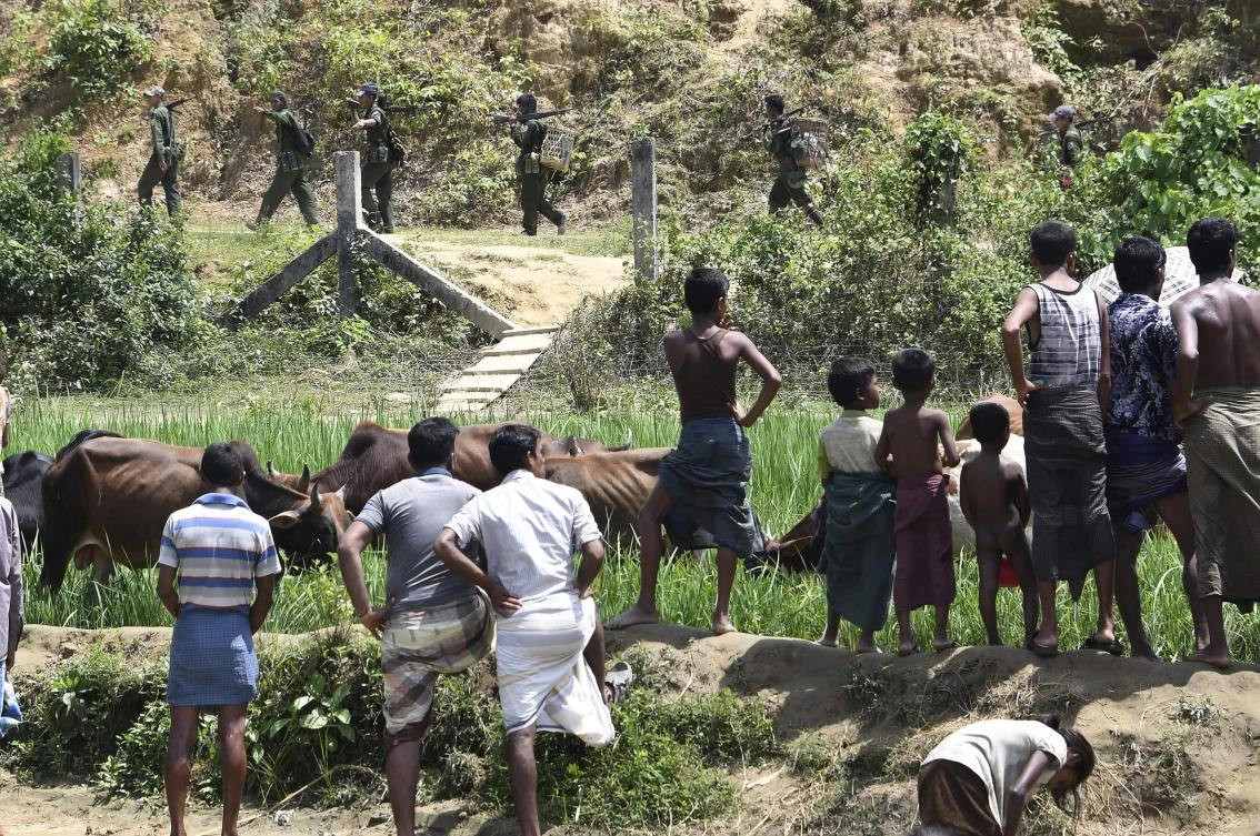 Rohingya Muslim refugees in Jalpatoli refugee camp, in the no-man's land area between Myanmar and Bangladesh, watch as Myanmar soldiers patrol on the other side of the border, near Gumdhum village in Ukhia. (AFP)