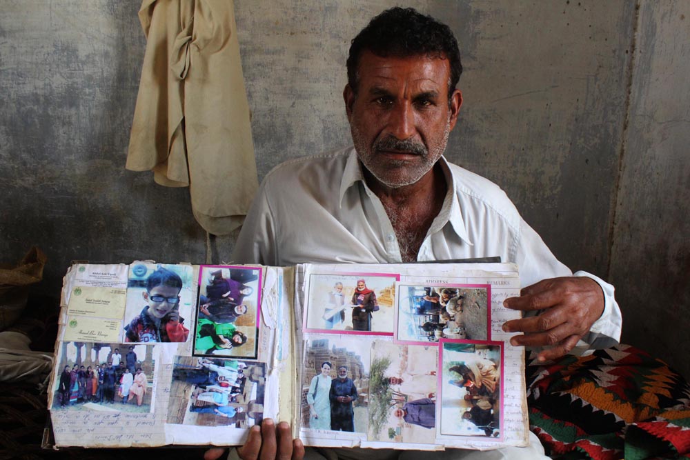 Muhammad Farooq has been associated with Chaukhandi for the past 35 years. He shows guest book with photos and expressions of the visitors. (Photo Arab News/ M.F. Sabir)