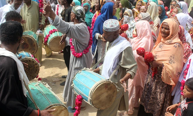 Members of Afro-Pakistani Sheedi community beat drums at the annual festival, as the devotees perform Dhamal.