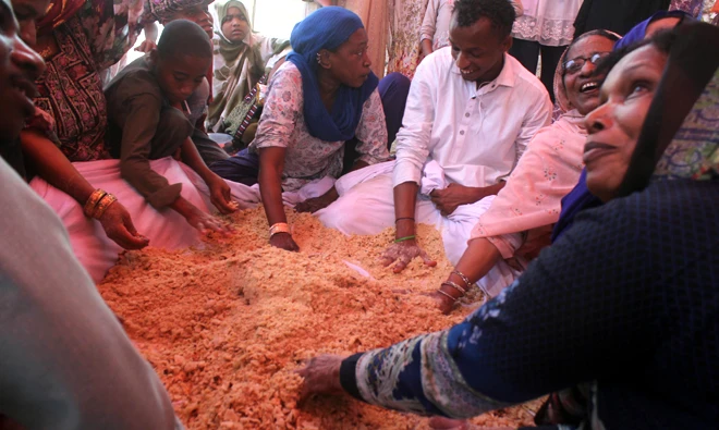 Local Sheedi community members preparing “Khutti,” a sweet prepared from wheat, almond and pistachio to be distributed among the devotees.