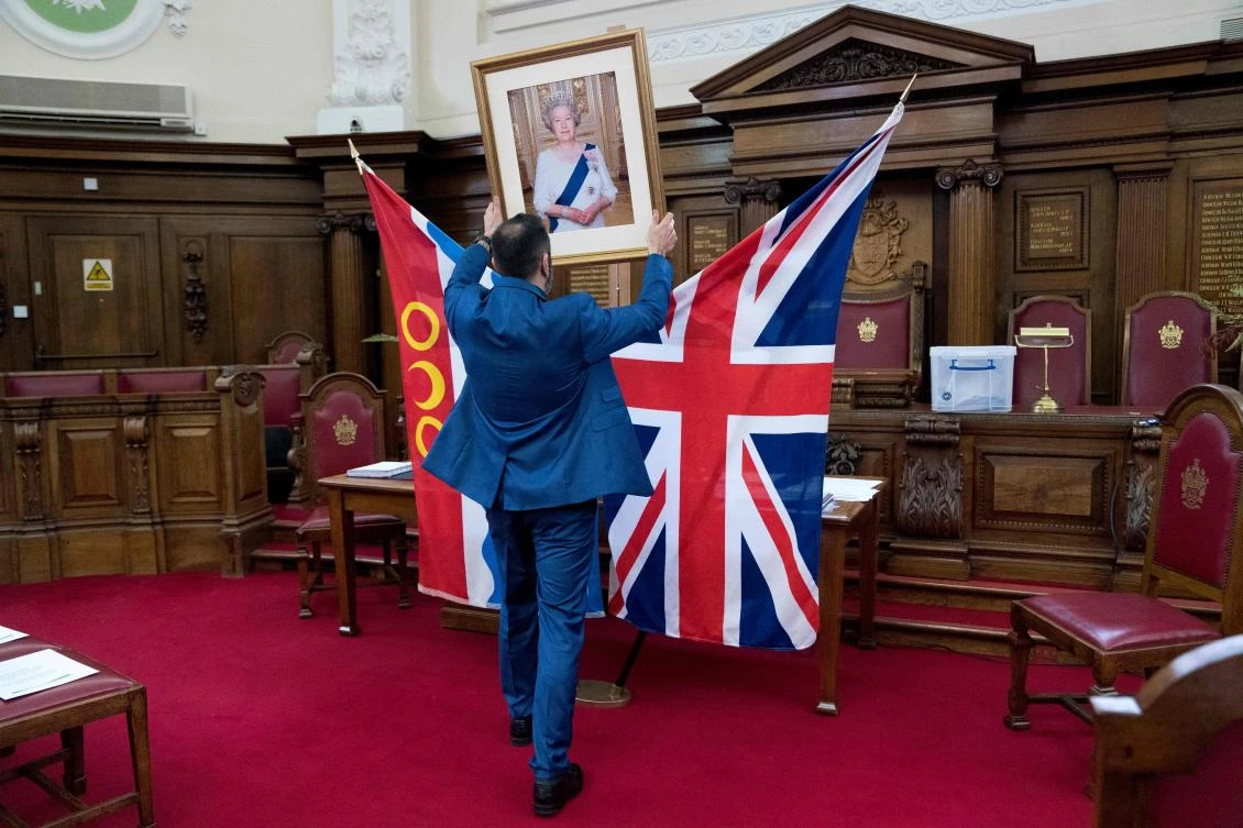 Deputy Superintendent Registrar, Dion Goncalves, moves a portrait of Britain's Queen Elizabeth II into position ahead of a citizenship ceremony at Islington Town Hall, in north London. (AFP)