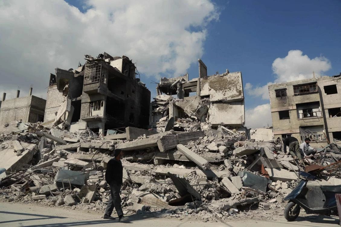 A resident walks past buildings destroyed earlier in Syrian air strikes, in the rebel-held town of Douma in the eastern Ghouta region. UN humanitarian supplies have been held up as there has been no let up in fighting despite a cease-fire resolution. (AFP)
