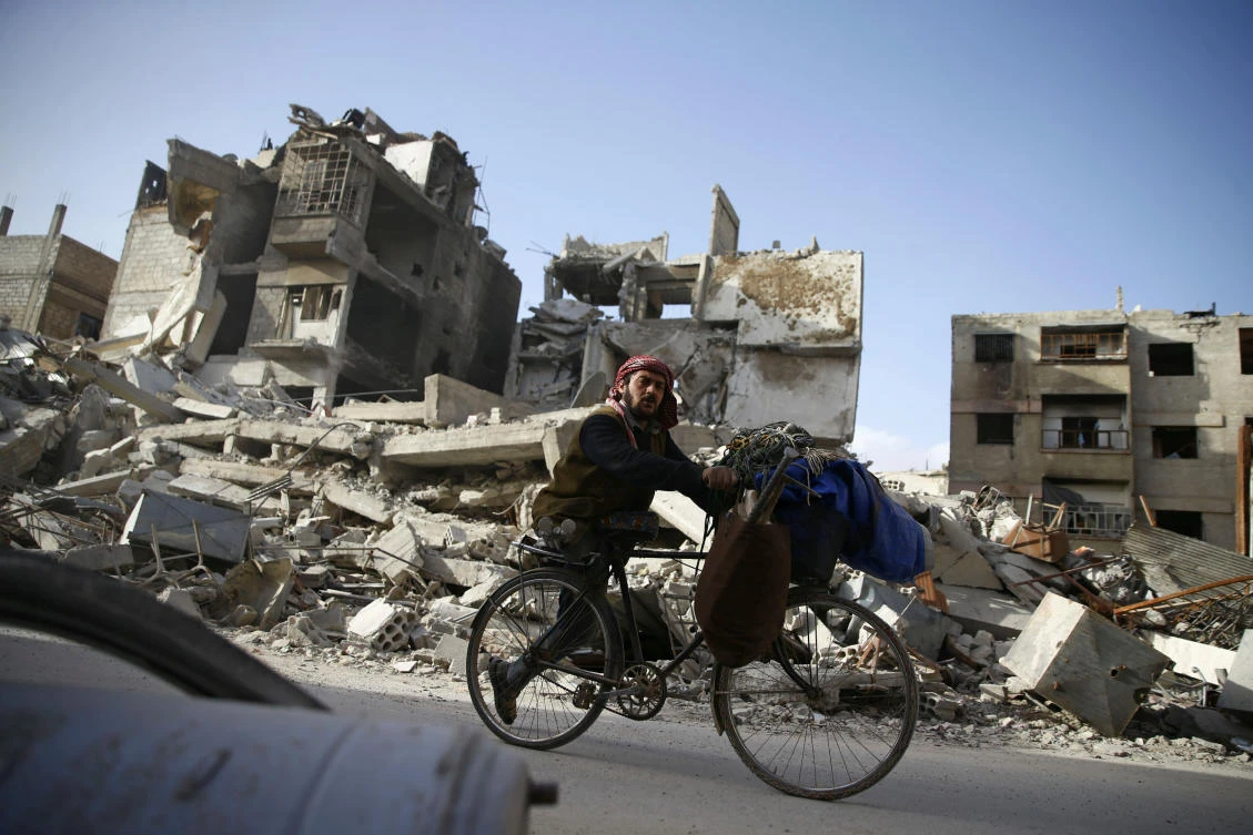 Above, a man rides a bicycle past damaged buildings in the besieged town of Douma in eastern Ghouta. The UN Human Rights Council in Geneva will hold an urgent debate on eastern Ghouta, at Britain’s request. (Reuters)