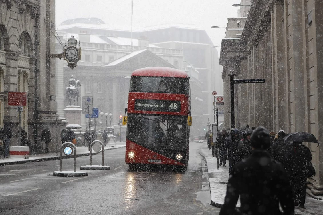 A red London bus makes it’s way through the snow as a blizzard hits central London on March 2, 2018. (AFP)
