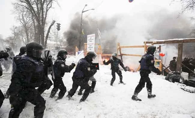 Riot police try to destroy a tent camp installed by activists of the Movement of New Forces, the political party led by Mikheil Saakashvili, as protesters fire tires in Kiev, Ukraine early Saturday. (AP)