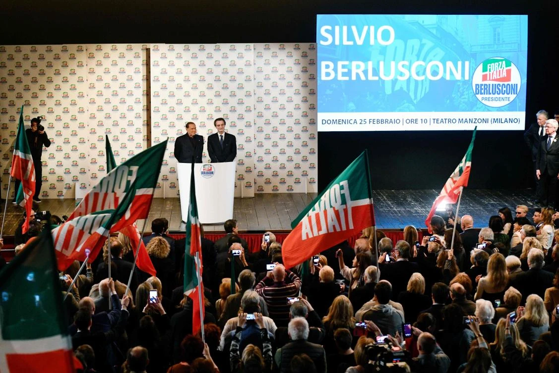 Leader of the Italian right-wing party Forza Italia (Go Italy) Silvio Berlusconi (L) and Forza Italia's Lombardia candidate Attilio Fontana (R) are greeted by supporters as they arrive on stage for a campaign rally in Milan. (AFP)