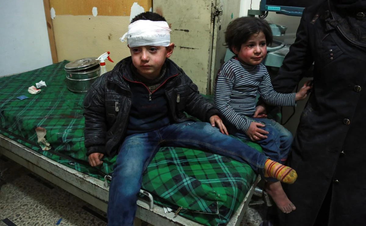 A bandaged Syrian child sits on a bed next to another child after receiving medical attention at a makeshift hospital in the rebel-held town of Douma, in the besieged Eastern Ghouta region on the outskirts of the capital Damascus, following reported regime bombardment on March 3, 2018. (AFP)
