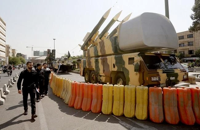 People walk past missile defence systems displayed on Baharestan square in Tehran. (AFP)