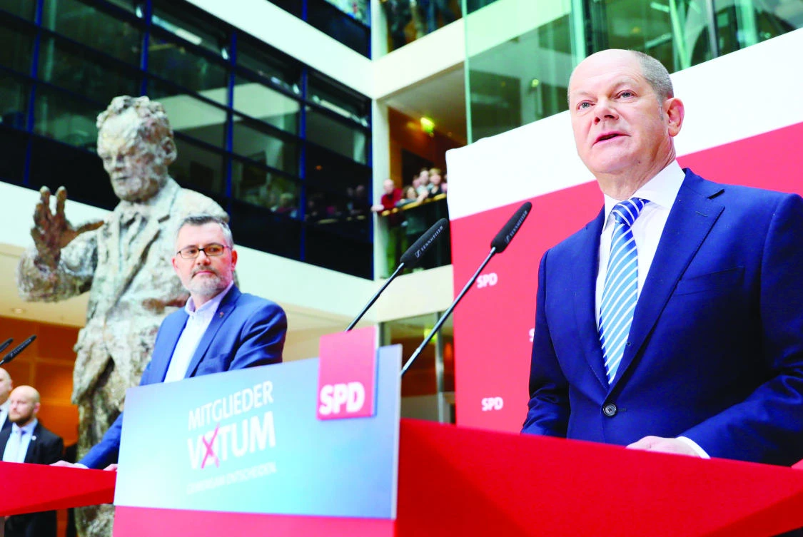 Olaf Scholz, right, interim leader of Germany's Social Democrats (SPD) party, speaks after the SPD's treasurer Dietmar Nietan announced the result of the SPD party members' referendum on whether or not to join a new coalition government with German Chancellor Angela Merkel's conservatives, during a press conference on Sunday. (AFP)