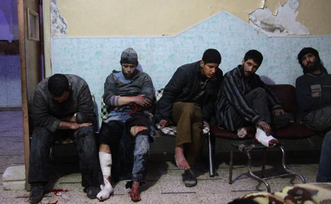 Wounded Syrian men are seated at a makeshift hospital in the rebel-held town of Douma, following air strikes by regime forces on the besieged Eastern Ghouta region on the outskirts of the capital Damascus on February 20, 2018. (AFP / Hamza Al-Ajweh)