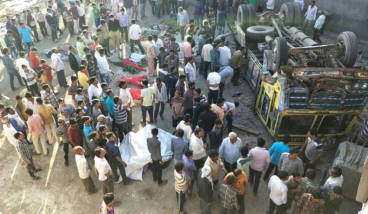 Onlookers gather around the bodies of passengers who had been travelling in a truck that plunged off a bridge in Bhavnagar district, about 200km from Ahmedabad in India's western Gujarat state, on March 6, 2018. (AFP)