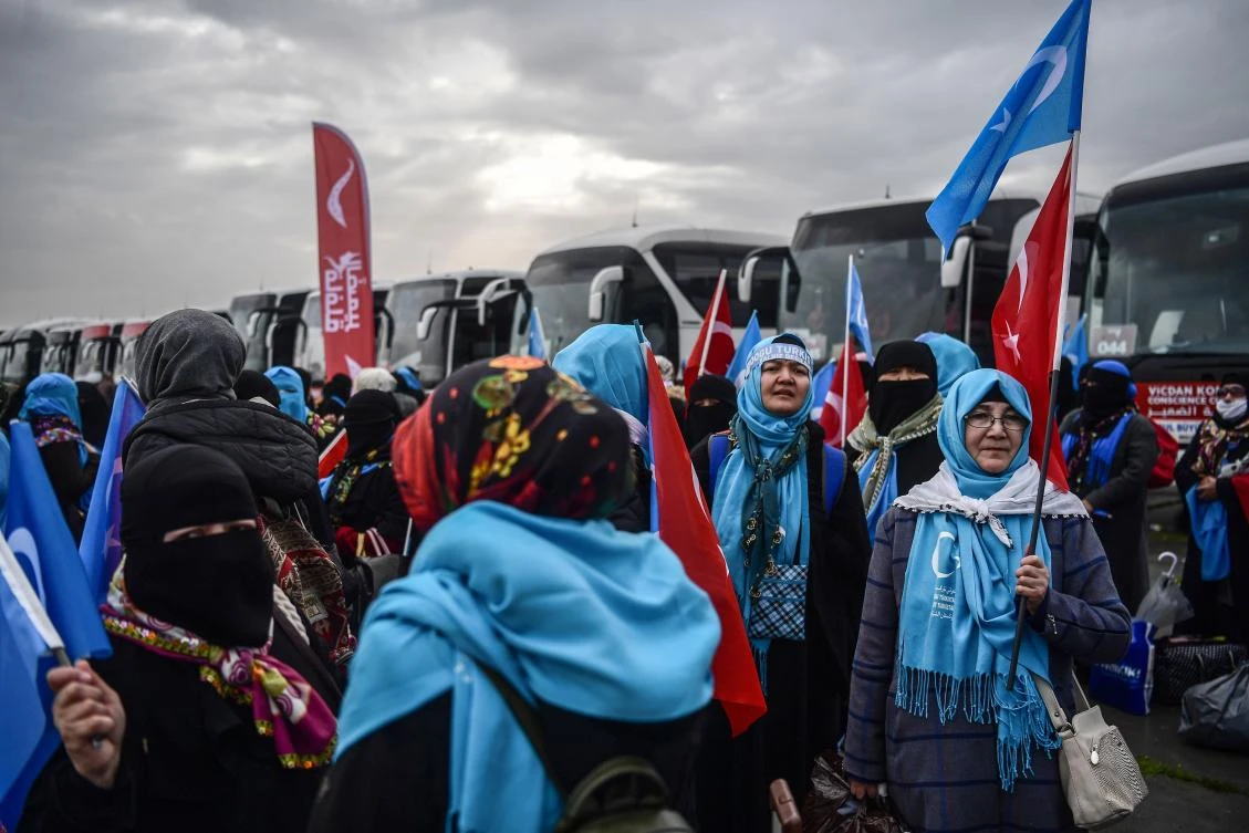 Women sing the rain as they prepare to embark on buses in Istanbul on March 6, 2018 ahead of a "Conscience Convoy" organizeed by Turkish Humanitarian Aid Foundation. (AFP)