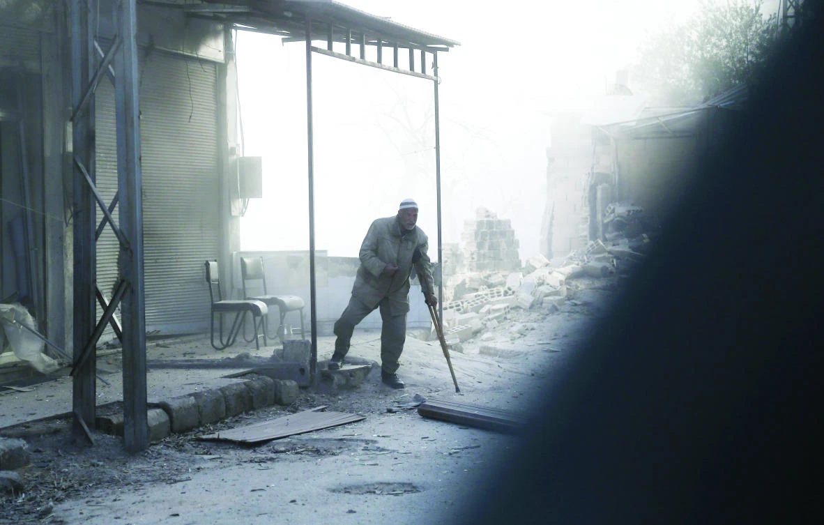 A wounded man walks in the street covered in dust following regime bombardments on Eastern Ghouta on Monday. The regime assaults in the region caused more civilians death on Tuesday. (AFP)