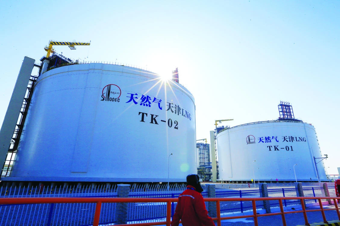 A Sinopec worker walks past liquefied natural gas (LNG) storage tanks at an LNG terminal in Tianjin. (REUTERS)