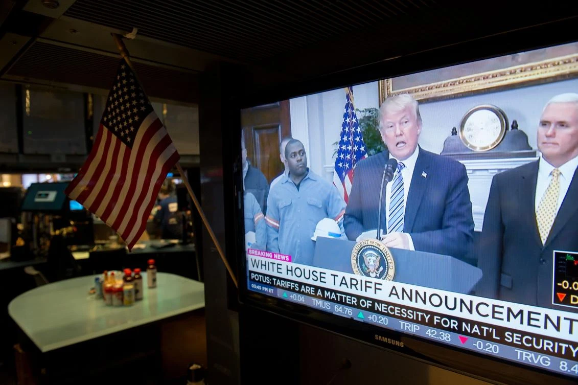 US President Donald Trump speaks on television as traders work on the floor of the New York Stock Exchange. Global markets have moved on controversial new US tariffs on imported steel and aluminum amid worries the move could ignite a global trade war. (AFP)
