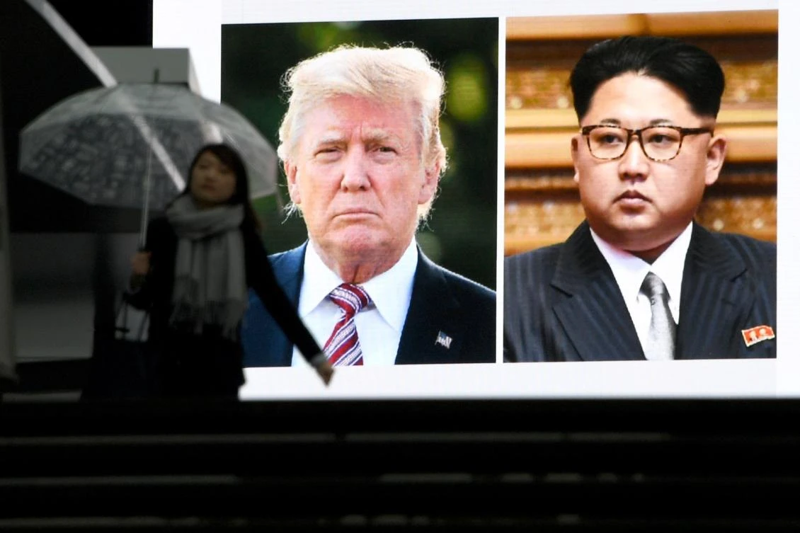 A pedestrian walks in front of a huge screen flashing a news report relating to US President Donald Trump and North Korean leader Kim Jong agreeing to meet for talks in Tokyo on March 9, 2018. (AFP)
