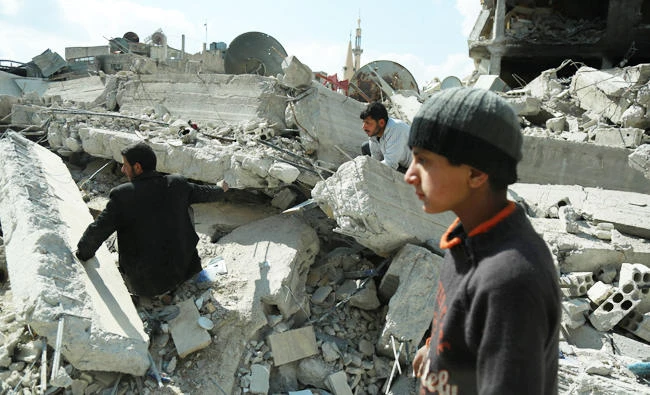 Syrian civilians search for survivors amid the rubble of buildings which were destroyed earlier in regime air strikes, in the rebel-held besieged town of Douma in the eastern Ghouta region, on the outskirts of the capital Damascus, on February 28, 2018. (AFP)