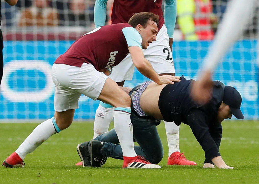 West Ham United's Mark Noble clashes with a fan who invades the pitch. (Reuters)