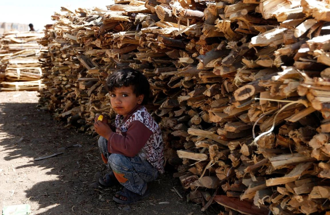 A Yemeni boy sits near firewood for sale amid ongoing cooking gas shortages in the Yemeni capital Sanaa, on March 6, 2018. (AFP)