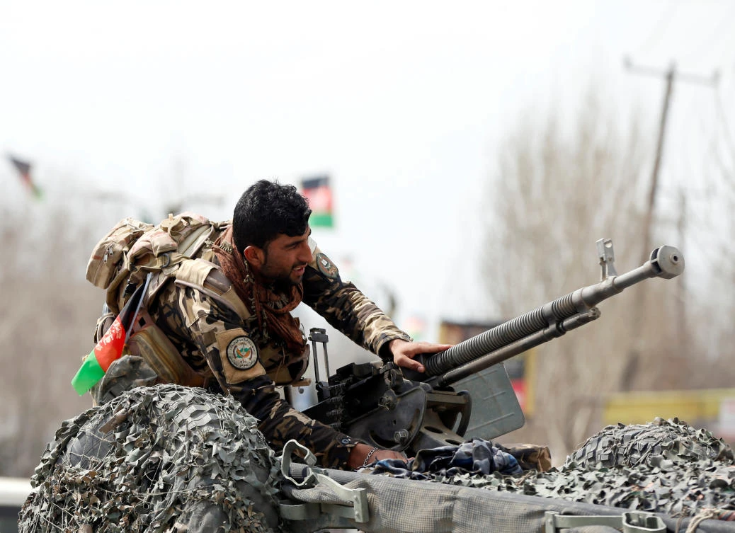 A member of the Afghan security forces prepares his machine gun at the site of a suicide bomb attack near a Shiite mosque in Kabul on March 9. (Reuters)