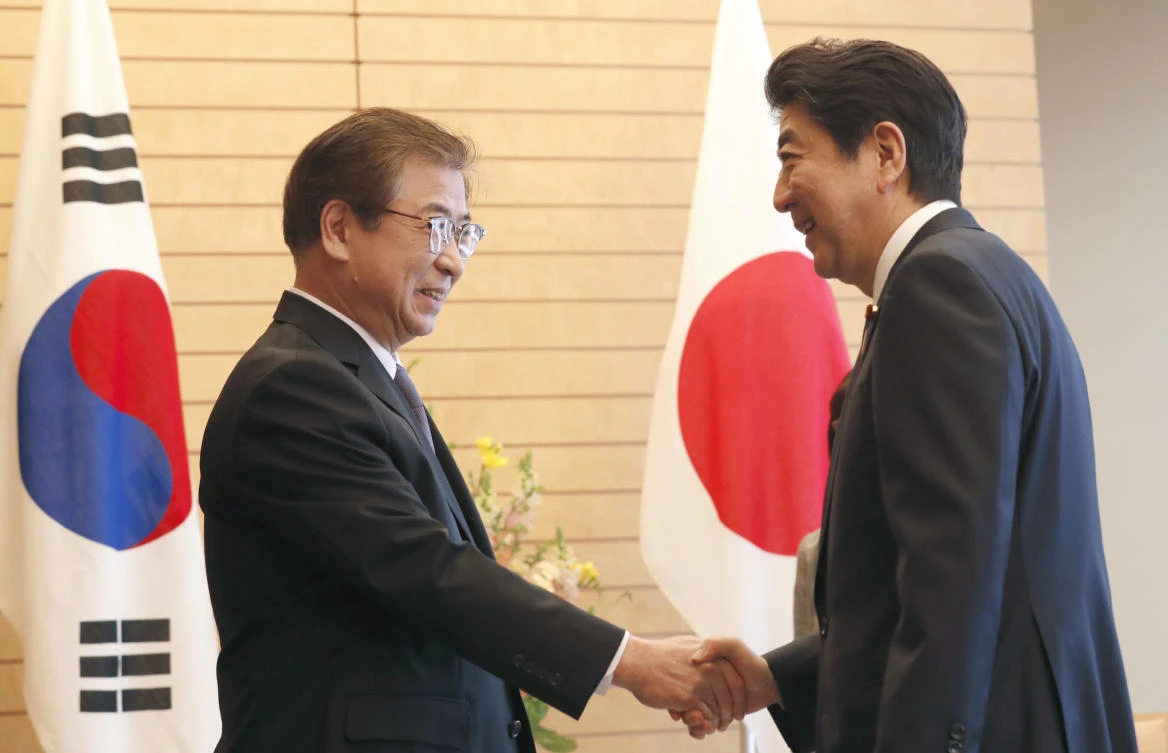 Japanese Prime Minister Shinzo Abe greet South Korea’s intelligence chief Suh Hoon at the start of their meeting on Tuesday in Tokyo. (AP)