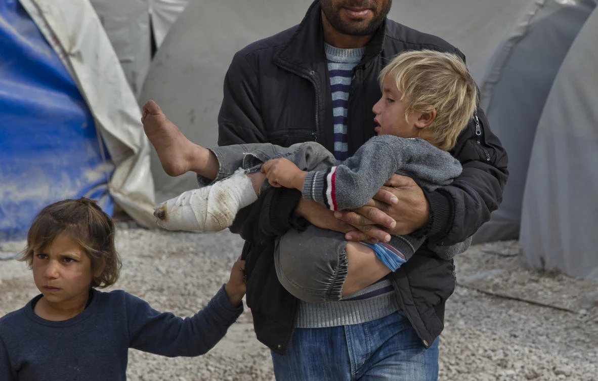 A Syrian Kurdish refugee from the Kobani area carries an injured child at a camp in Suruc, on the Turkey-Syria border. (AP)