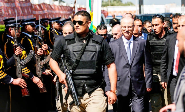 Palestinian Prime Minister Rami Hamdallah (2nd-R), escorted by his bodyguards, is greeted by police forces of the Islamist Hamas movement (L) upon his arrival in Gaza City, in this March 13, 2018 photo. (AFP)
