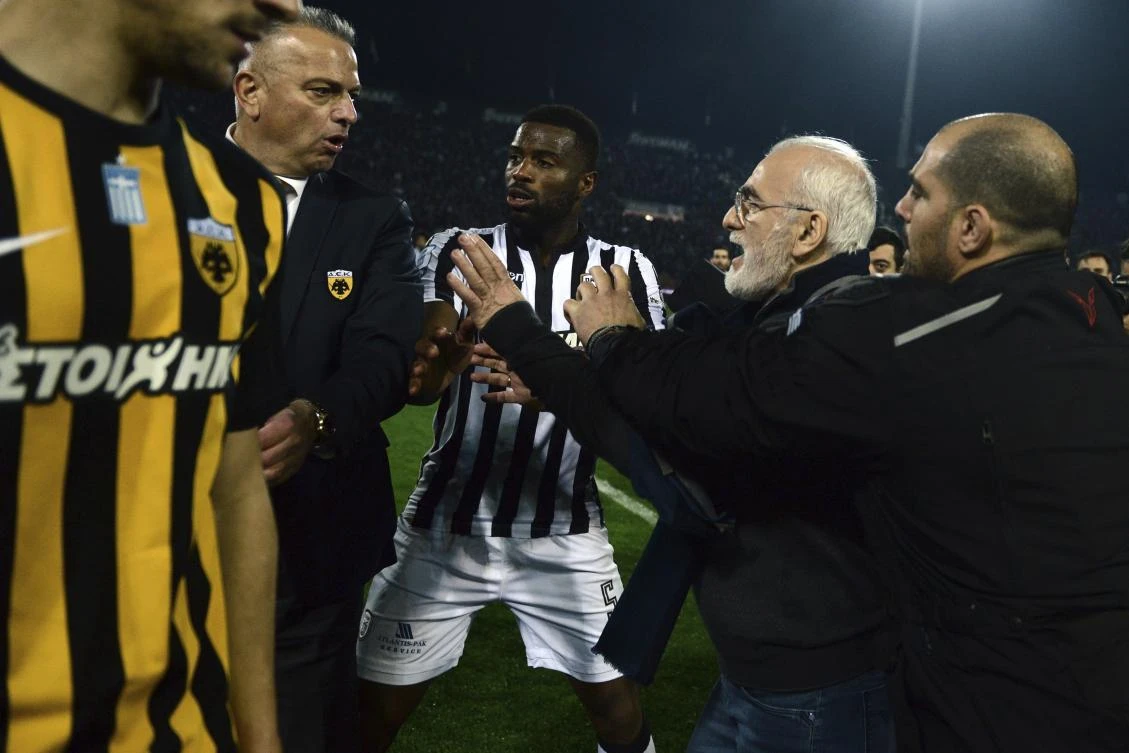 PAOK owner, businessman Ivan Savvidis, second right, approaches AEK Athens' Manager Operation Department Vassilis Dimitriadis, second left, as his bodyguard and PAOK's player Fernando Varela from Portugal, center, try to stop him during a Greek League soccer match. (AP)