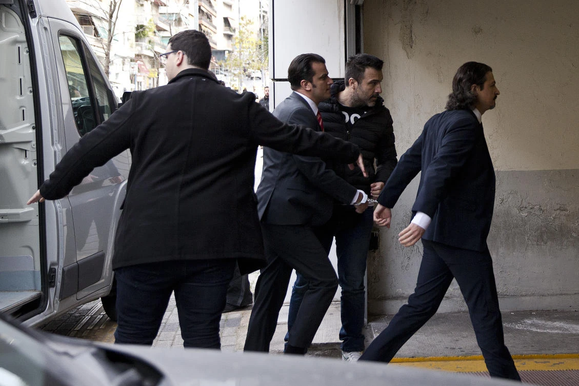 Greek police officers in plain clothes escort two of the eight Turkish servicemen, right and third right, to the appeals court in Athens, on Friday March 16. (AP)