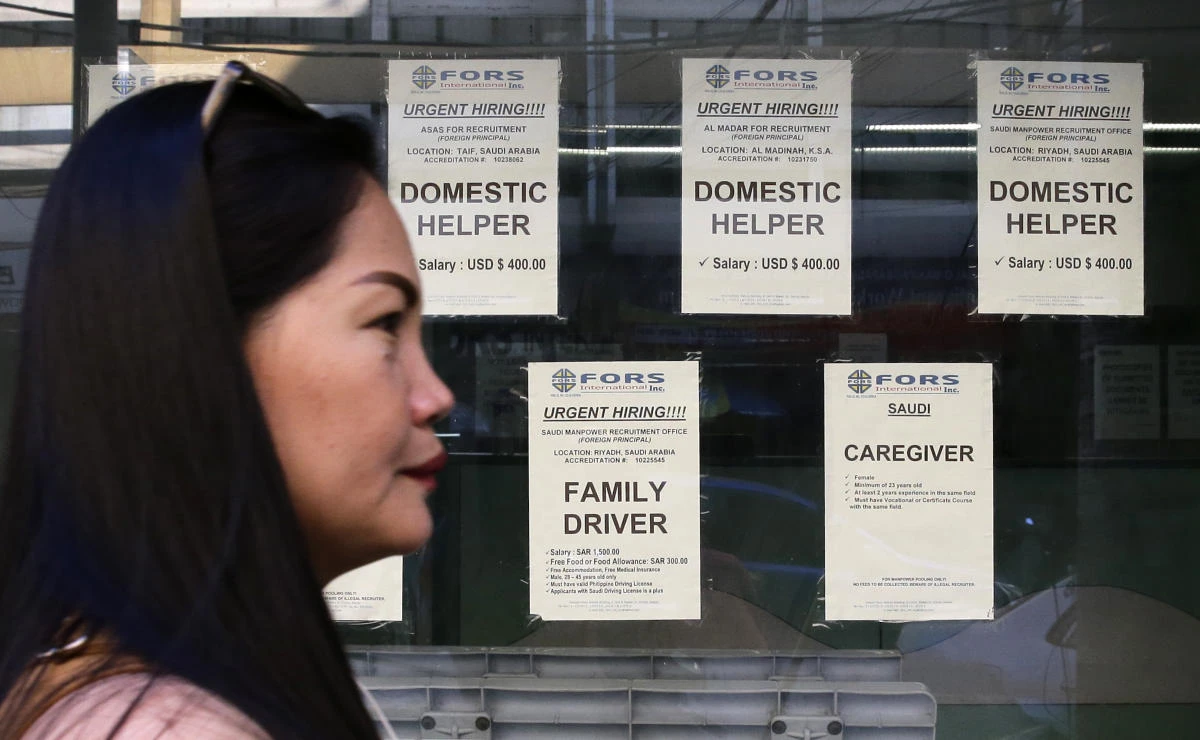 A woman passes help wanted signs outside a recruitment agency for jobs abroad in Manila, Philippines, Friday, Mar. 2, 2018. (AP)