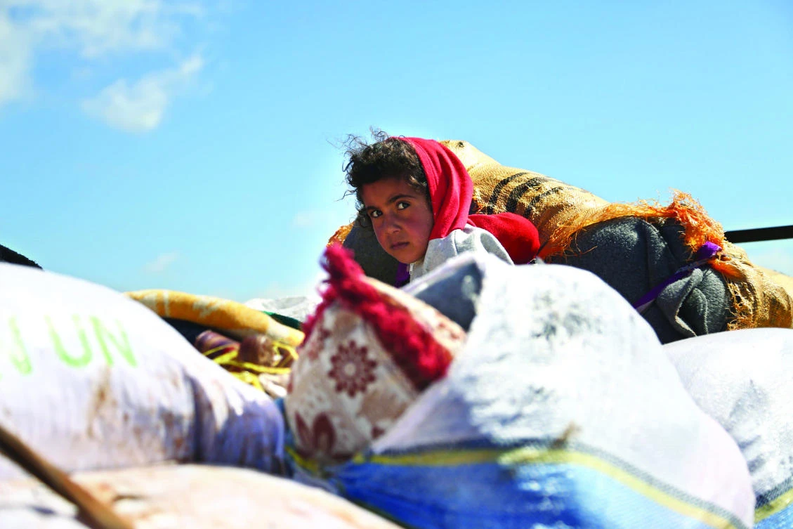 A Syrian girl waits at a check point in the village of Anab ahead of crossing to the Turkish-backed Syrian opposition side on Sunday, as civilians flee the city of Afrin in northern Syria. (AFP)