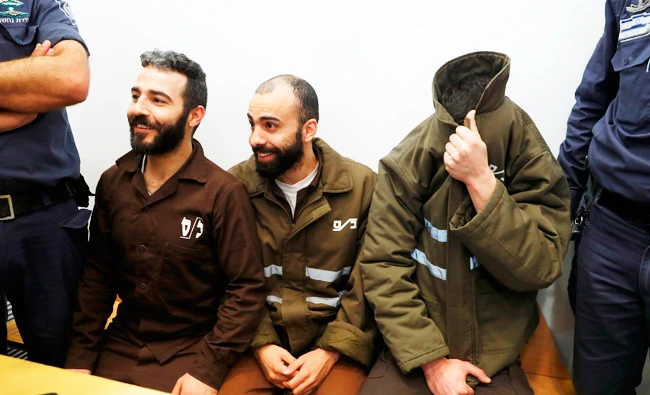 French national Romain Franck (R), 24, a worker at the French consulate, and Palestinian Moufak al-Ajluni (L) and Mohamed Katout (C) appear in court the southern Israeli city of Beer Sheva on March 19, 2018, to face charges of smuggling guns from Gaza. (AFP)