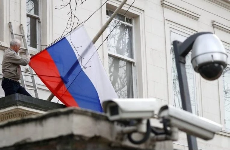 A man takes the flag off the flagpole outside the consular section of Russia’s Embassy in London. (Reuters)