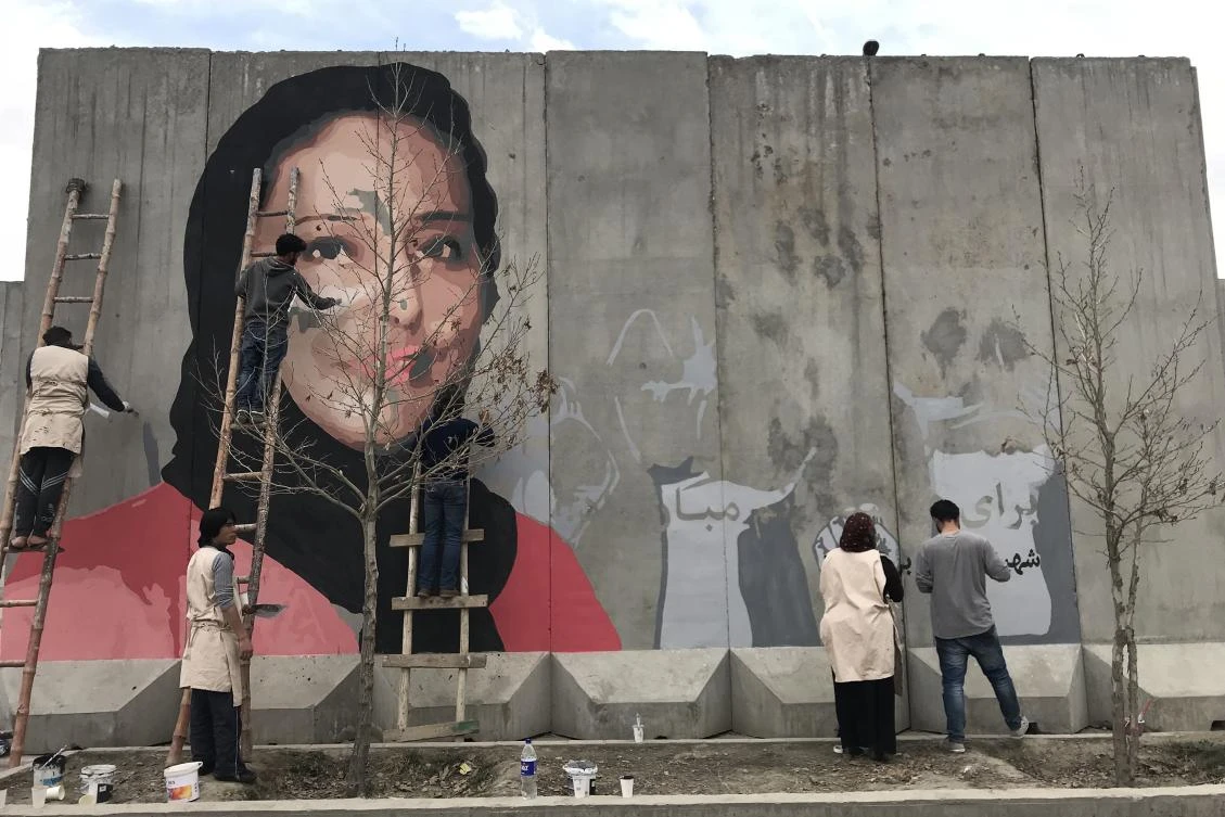 This handout from the Afghan social activist group ArtLords taken on March 8, 2018 shows artists painting a mural of Hamida Barmaki, who, along with her husband and children, was killed in a 2011 suicide attack on a supermarket, on a blast wall near the home of warlord Gulbuddin Hekmatyar, whose followers had carried out the attack, in Kabul. Over the past four years the social activist group ArtLords has turned Kabul’s grey maze of concrete barricades — shaped like a wide-based inverted ‘T’ to provide protection from bomb blasts — into a canvas to tackle issues such as rampant corruption and abuse of power. The group’s artists are calling out Afghanistan’s most powerful by depicting people killed by warlords in giant murals in public places. — -----EDITORS NOTE --- RESTRICTED TO EDITORIAL USE — MANDATORY CREDIT “AFP PHOTO / ArtLords” — NO MARKETING — NO ADVERTISING CAMPAIGNS — DISTRIBUTED AS A SERVICE TO CLIENTS — NO ARCHIVES — MANDATORY MENTION OF THE ARTIST UPON PUBLICATION
