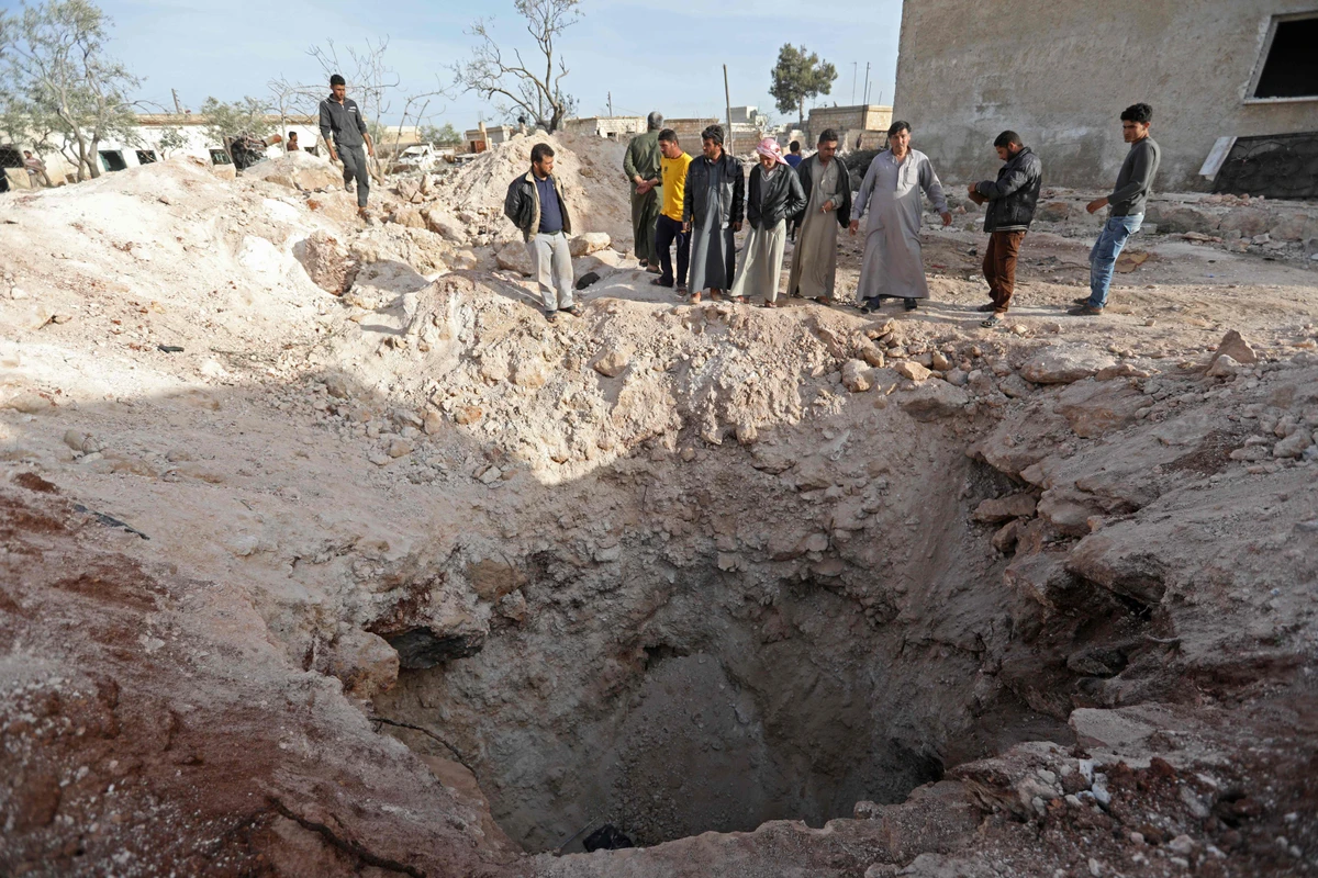 Syrian men gathered outside a crater left over a collapsed make-shift bomb shelter after an air strike left over a dozen school-children killed in the town of Kafr Batikh in the northwestern Idlib province. (AFP)