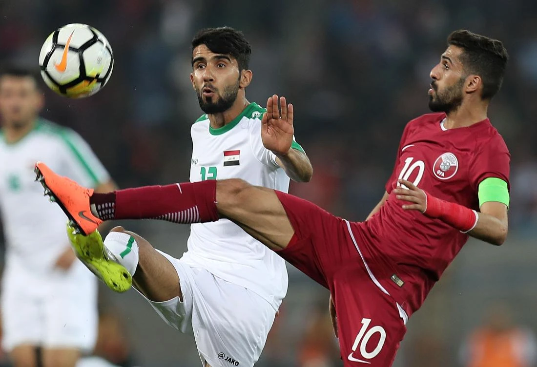 Iraq's Bashar Resan Bonyan vies for the ball against Qatar's captain Hassan Khalid Alhaydos during the international friendly football match between Iraq and Qatar at the Basra Sports City Stadium in Basra on March 21, 2018. / AFP / KARIM JAAFAR