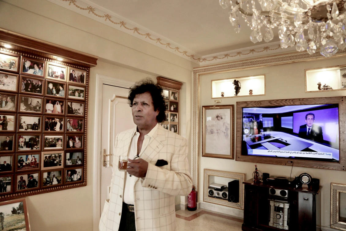 Ahmed Gaddaf Al-Dam, cousin of Libya’s former president Muammar Qaddafi, speaks to The Associated Press, while the news on his television shows Former French President Nicolas Sarkozy in the background, at his apartment in Cairo, Egypt, Mar 22, 2018. (AP)