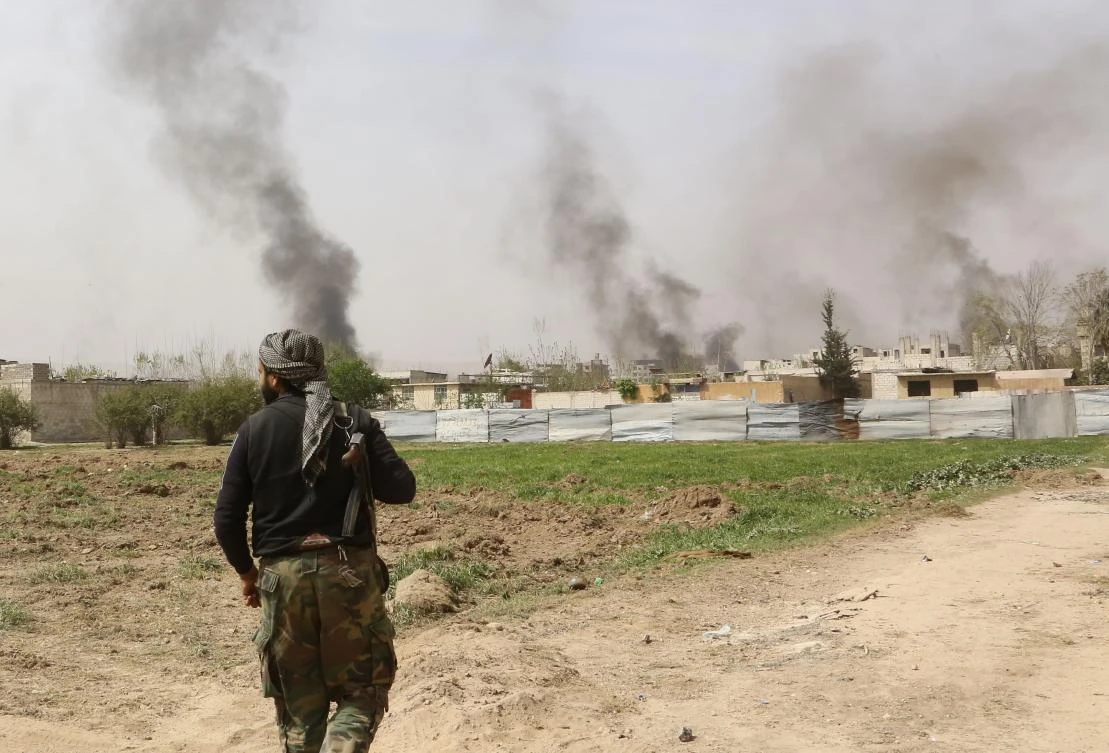 Smoke can be seen rising from the Eastern Ghouta town Hazeh, as a Syrian rebel is pictured on the government side where a group of opposition fighters handed themselves over , after a deal was reached in Ain Tarma and a cease-fire is in place to prepare for the evacuation. (AFP)