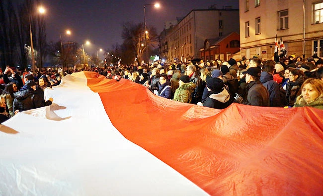 People carry the Polish flag during a protest against plans to further restrict abortion laws in Warsaw, Poland on Friday. (REUTERS)