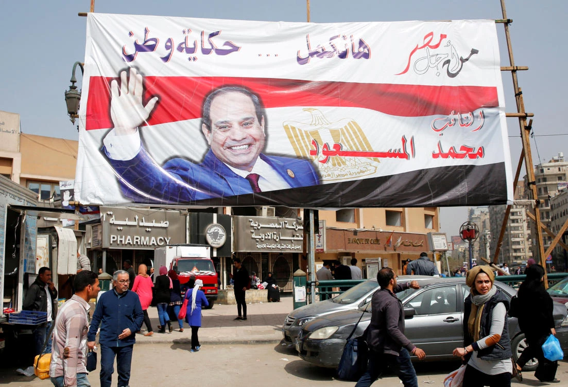 People walk by a poster of Egyptian President Abdel Fattah El-Sisi for the upcoming presidential election, in Cairo, Egypt. (Reuters)
